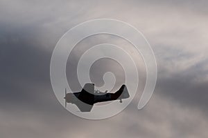 Silhouette shot of vintage military aircraft flying against a cloudy sky