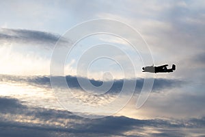 Silhouette shot of vintage military aircraft flying against a cloudy sky