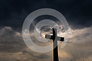 Silhouette of a simple catholic cross, dramatic stormclouds photo