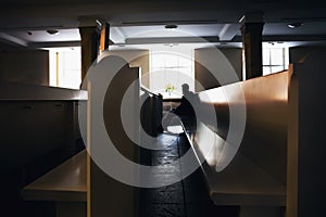 Silhouette of sinful man praying in church seating on pews