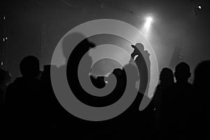 A silhouette of singer rap musician during live concert in dark light.