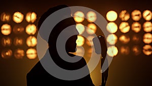 Silhouette singing man vocalist using microphone on show stage nightclub closeup