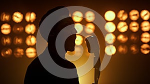 Silhouette singing man vocalist using microphone on show stage nightclub closeup