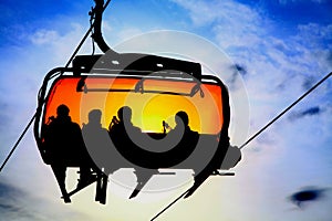 Silhouette of skiers on ski lift chair