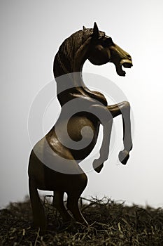 Silhouette skittish horses in grass filed, the wood horse sculpture on white background photo