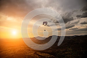 Silhouette of sky diver flies on background of sunset sky