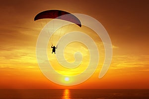 Silhouette of skydiver on background sunset