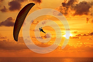 Silhouette of skydiver on sunset and the sea