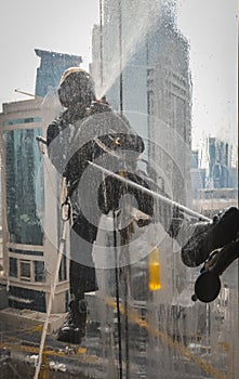 Silhouette of skyscraper windows Cleaner washing a window at the City Centre in Doha,