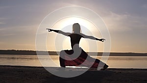 Silhouette of a slender girl do warrior namaste yoga pose at sunset. Seaside