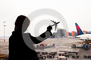 Silhouette of a small airplane model on airport in kids hands