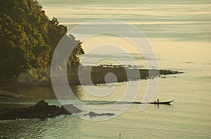 Silhouette small boat off the coast in sunrise light misty morning