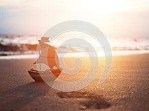 Silhouette small boat toy on sand at sunset beach