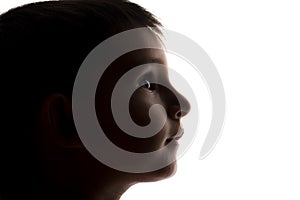 Silhouette of a small boy face looking upwards, kids head profile