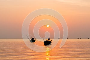 Silhouette of Small fishing boats on the sea during sunrise