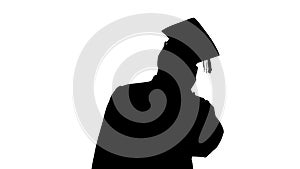 Silhouette Smiling african american male student in graduation robe talking on the phone sharing happy news.
