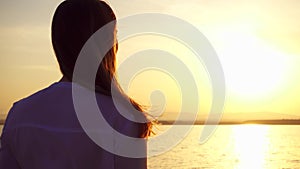 Silhouette of smiling young woman at sunset on lake. Female figure at golden hour in slow motion