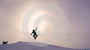 Silhouette of snowboarder jumping on mountain ski slope.