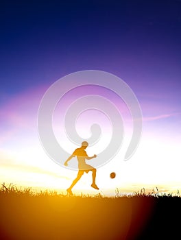 Silhouette of soccer player kicks ball photo