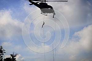 Silhouette Soldier rappelling from helicopter in blue sky