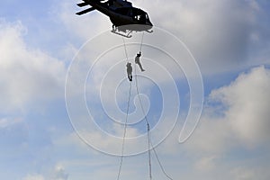 Silhouette Soldier rappelling from helicopter in blue sky