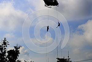 Silhouette Soldier rappelling from helicopter in blue sky