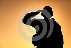 Silhouette of soldier salutes on sunset background