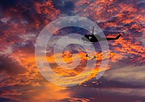 Silhouette soldiers in action rappelling climb down from helicopter with military mission counter terrorism