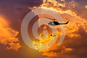 Silhouette soldiers in action rappelling climb down from helicopter with military mission counter terrorism