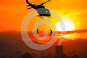 Silhouette Soldiers rappel down to attack from helicopter on with sunset and copy space add text Concept stop hostilities To pe