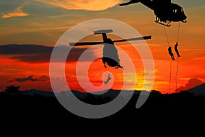 Silhouette Soldiers rappel down to attack from helicopter with sunset photo
