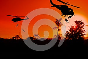 Silhouette Soldiers rappel down to attack from helicopter with sunset photo