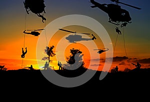 Silhouette Soldiers rappel down to attack from helicopter with sunset