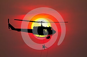 Silhouette Soldiers rappel down to attack from helicopter with warrior beware danger On the ground sunset Background blur