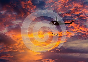 Silhouette soldiers in rappelling climb down from helicopter with military mission counter terrorism assault training on su