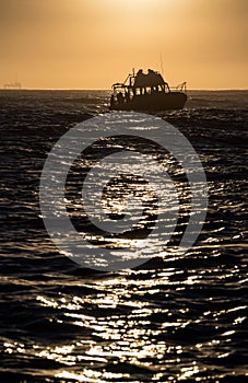 Silhouette of Speed boat in the ocean at sunrise.