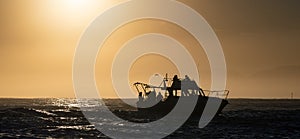 Silhouette of Speed boat in the ocean at sunrise.