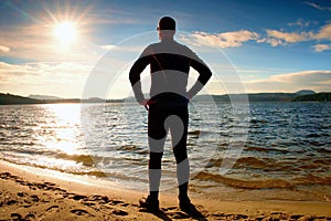 Silhouette of sport active adult man running and exercising on the beach. Calm water