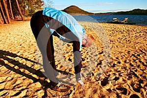 Silhouette of sport active adult man running and exercising on beach. Calm water, island and sunny sky