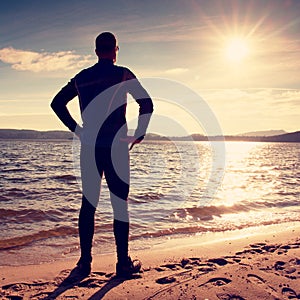 Silhouette of sport active adult man running and exercising on the beach. Calm water