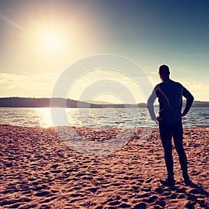 Silhouette of sport active adult man running and exercising on the beach. Calm water
