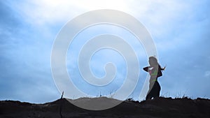 Silhouette sport girl walks on top of a hill