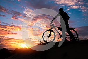 Silhouette of sports person cycling on the meadow on the beautiful sunset.