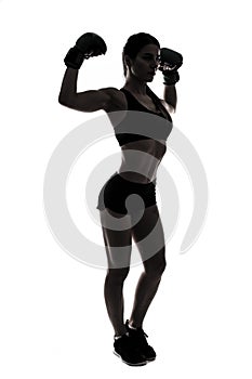 Silhouette sporty woman doing boxing exercises, making direct hit with dumbbells. Photo of muscular female wearing sportswear on w