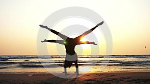 Silhouette of sporty young women practicing acrobatic element on the beach.