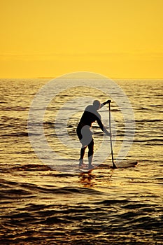 Silhouette of Stand up paddler at sunset, paddle board sport.