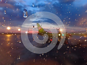 The silhouette of a standing plane at the airport through the glass with raindrops