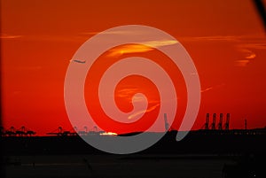 Silhouette of Statue of Liberty and Liberty Island in New York against an orange sunset sky