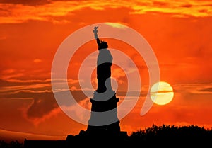 Silhouette of Statue of Liberty over dramatic sunset, New York, USA