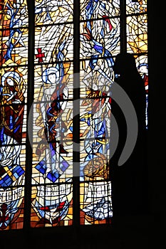 The silhouette of a statue is taking shape over a window in a church (France)